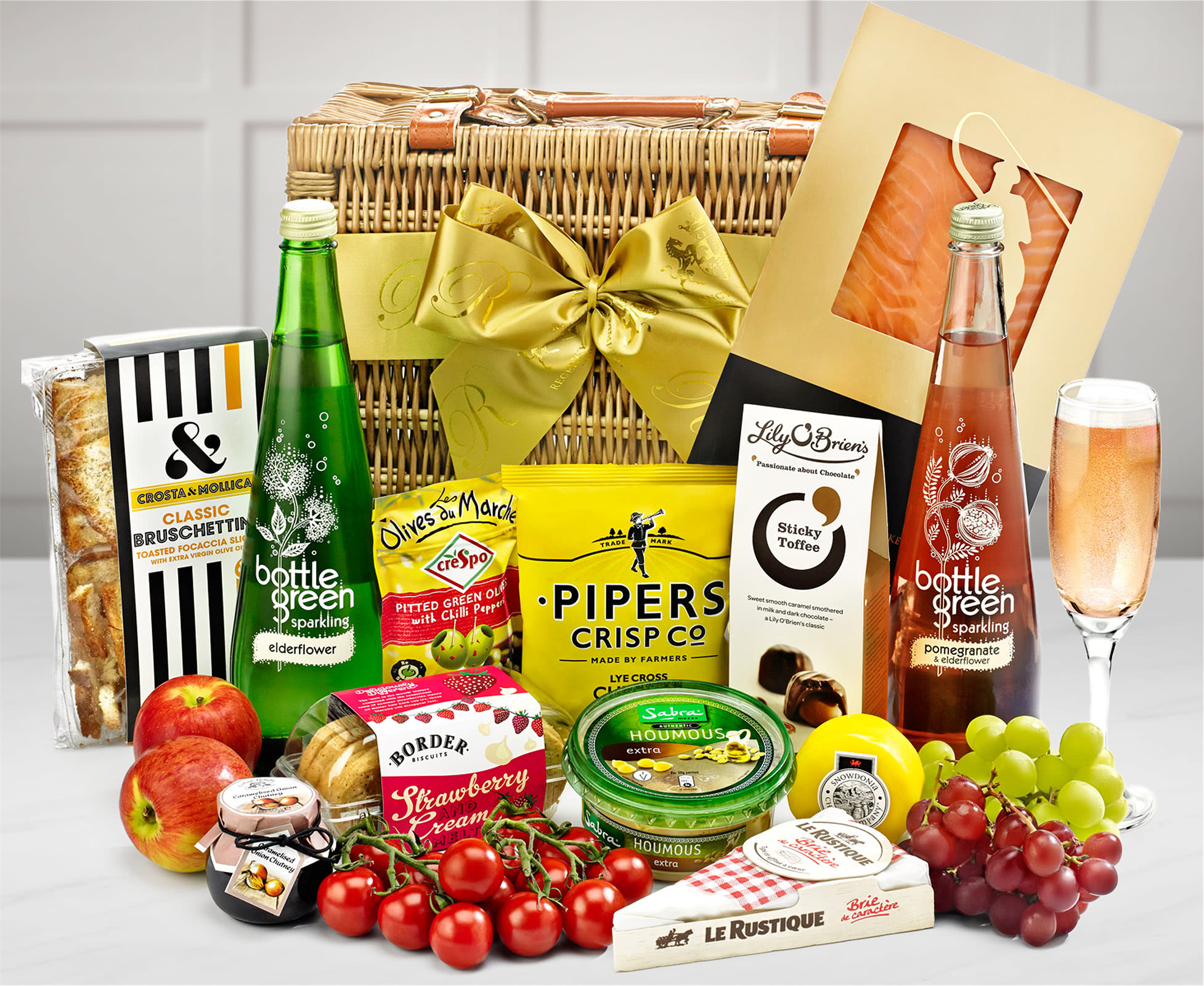 A picnic basket with with fruits, cherry tomatoes, cheeses, bruschetta and other finger foods