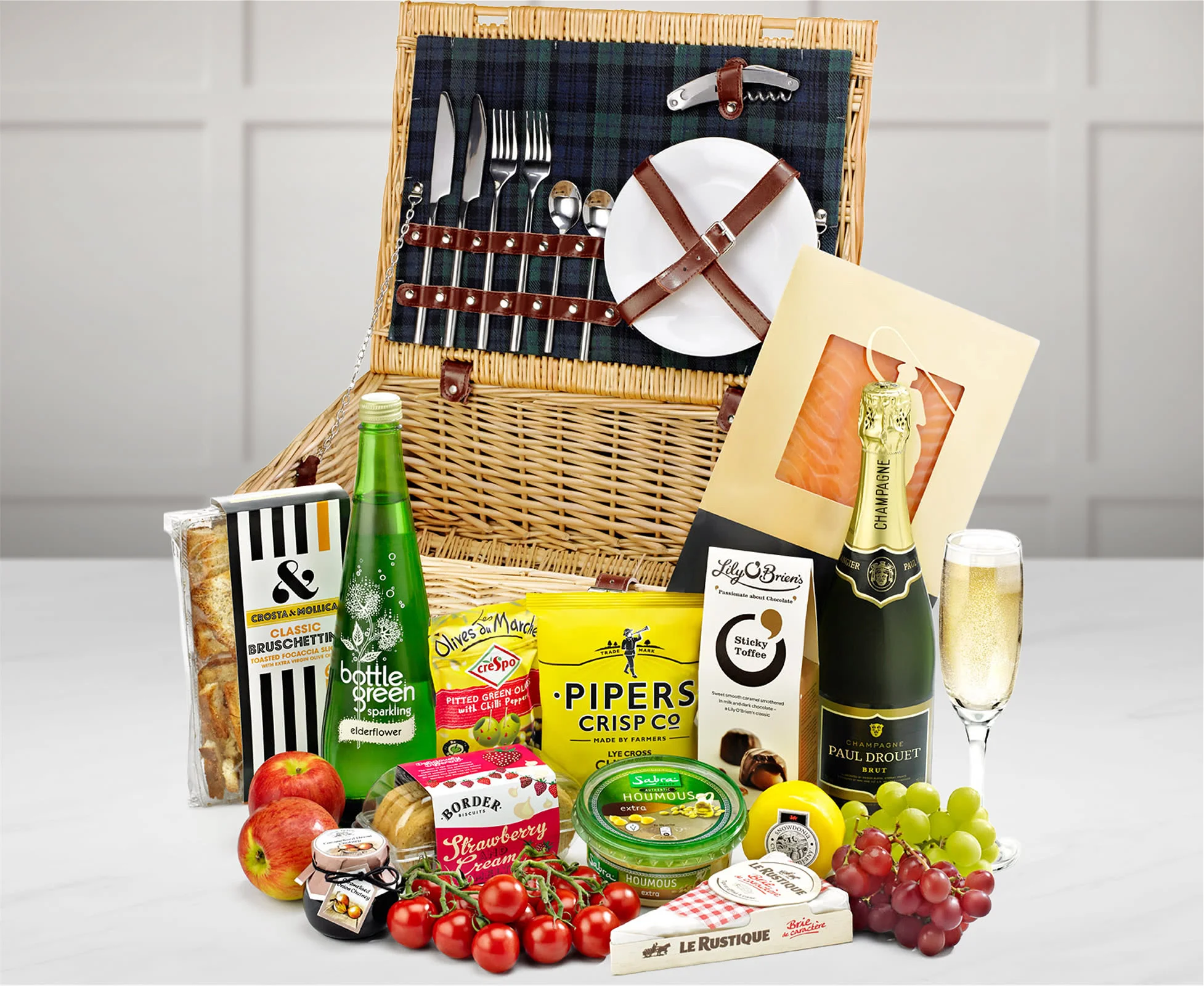 A fitted picnic hamper with picnic food and a bottle of champagne.